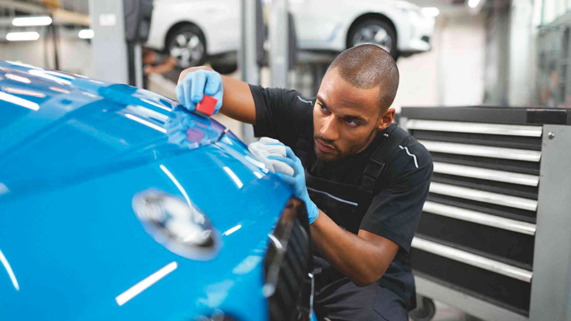 Vediamo un tecnico al lavoro sulla carrozzeria di una BMW in officina